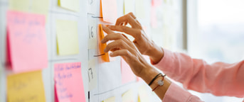 Une femme colle un post-it sur un mur Une femme colle un post-it sur un mur